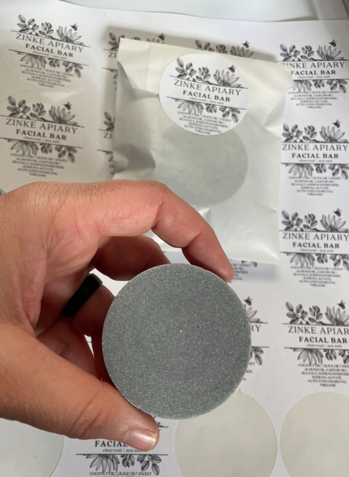 Hand holding a gray facial bar with Zinke Apathy branding in the background