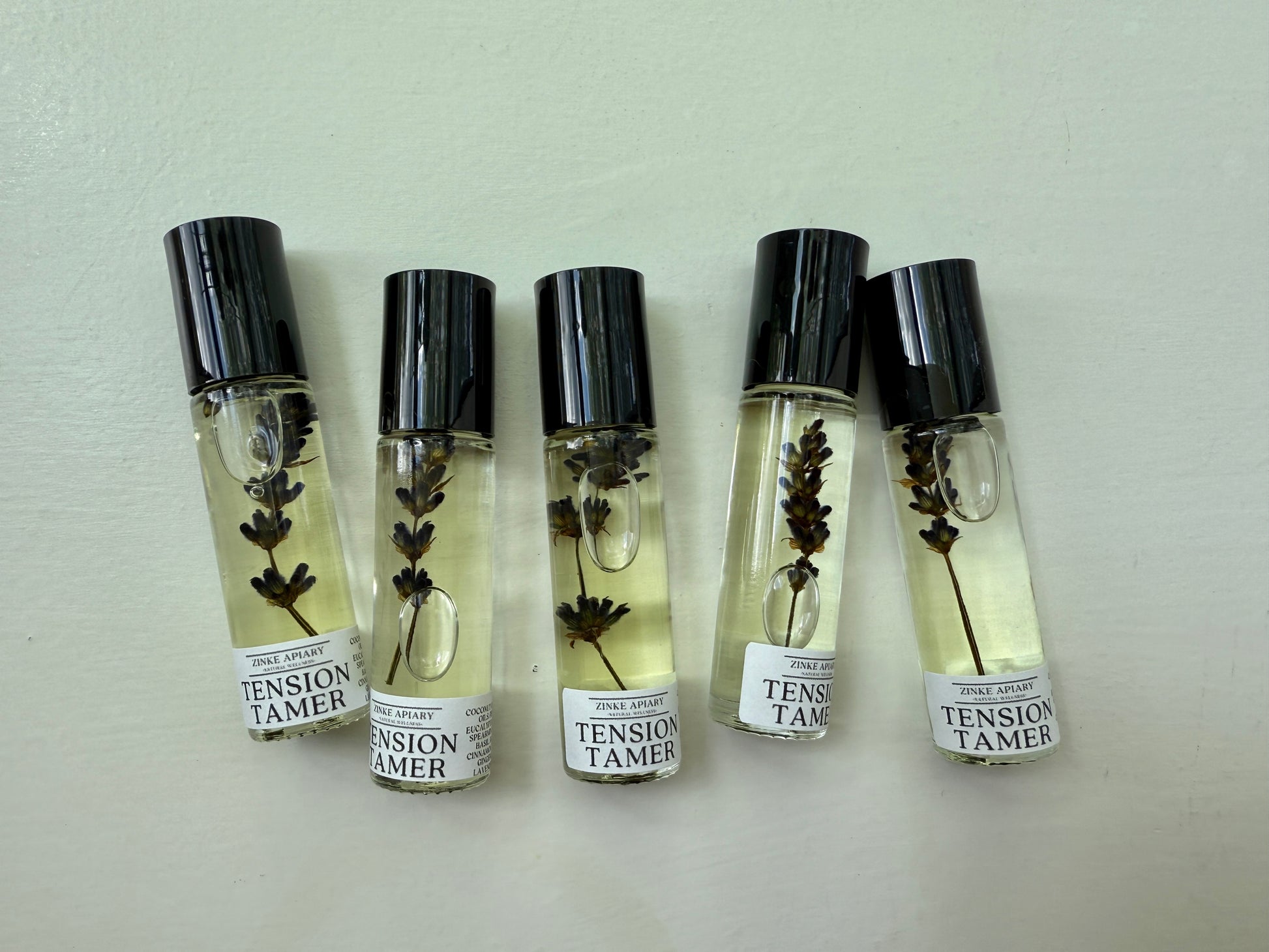 Five small bottles labeled 'Tension Tamer' with black caps on a light gray background.