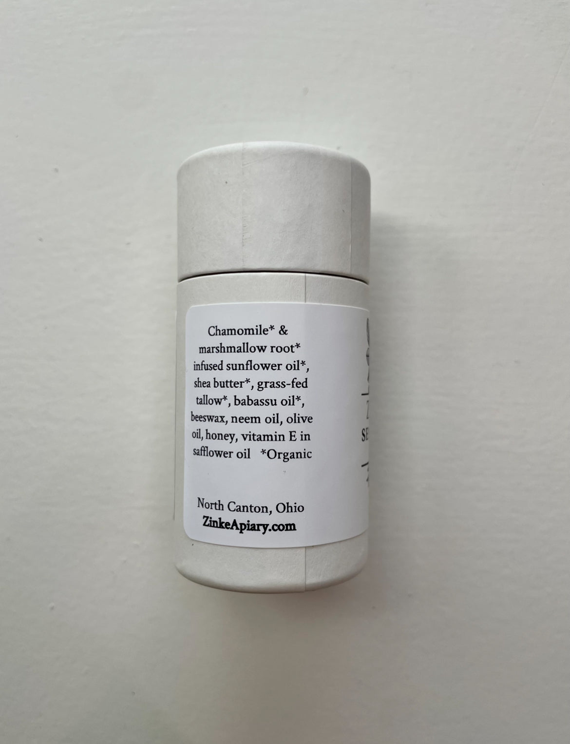 White cylindrical container with a label on a light gray background